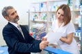 Female pharmacist at counter reading prescription with customer. Royalty Free Stock Photo