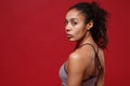 Side view of beautiful young african american sports fitness woman in sportswear posing working out isolated on red wall Royalty Free Stock Photo