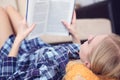 Beautiful young woman laying on the floor at home, reading a book, living room interior. Girl reading a book on the Royalty Free Stock Photo