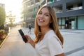 Side view of beauty happy woman looking at camera with phone in city Royalty Free Stock Photo
