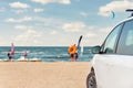 Side view of big family white suv van car parked at scenic sand seaside campsite camp coast of sea or ocean with blue