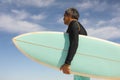 Side view of biracial senior man carrying surfboard at beach against sky on sunny day