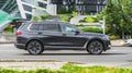 Side view of black BMW X7 car riding on the street on high speed. Shiny gray SUV car in motion. Urban scene with riding vehicle Royalty Free Stock Photo