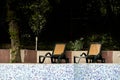 Side view of black and brown plastic sun loungers for relaxing on the hotel territory, backyard surrounded by trees Royalty Free Stock Photo