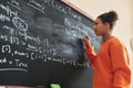 Side view black teenage girl writing on blackboard in school classroom Royalty Free Stock Photo