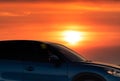 Side view of blue SUV car with sport and modern design parked on concrete road by sea beach at sunset. Electric car technology. Royalty Free Stock Photo