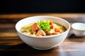 side view of a bowl of gumbo with shrimp on top