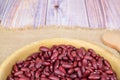 Side view of a bowl of raw red beans. The bowl sits on a rough napkin on a wooden surface Royalty Free Stock Photo