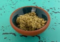 Side view of a bowl with a small portion of crushed sage leaf atop a green and black tabletop