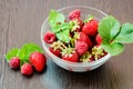 Side view of a bowl of strawberries and raspberries with mint leaves. Berries lie next to the bowl Royalty Free Stock Photo