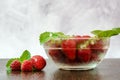 Side view of a bowl of strawberries and raspberries with mint leaves. Berries lie next to the bowl Royalty Free Stock Photo