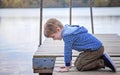 Side view of boy on dock looking in lake Royalty Free Stock Photo