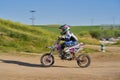 Side view of a boy performing stunt with motorcycle on motocross track