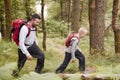 Side view of a boy walking on trail in a forest with his father, selective focus