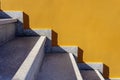 Geometrical view of marble stairs with light and shadow lines, and yellow painted wall.