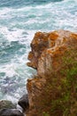 Side view of the brown part of the rock in the shape of a monkey against the background of a rough blue sea with large waves