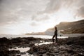 Side view brunette boy standing in the black swimsuit with a white surf in his hands on the shore Royalty Free Stock Photo