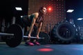Woman doing deadlift using barbell in gym.