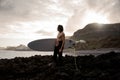 Side view brunette man standing in the black swimsuit with naked torso with a white surf in his hands on the shore Royalty Free Stock Photo