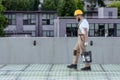 side view of builder in protective helmet and googles carrying bucket of cement at construction Royalty Free Stock Photo