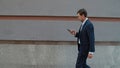 Side view business man walking with phone. Man using phone near modern building Royalty Free Stock Photo