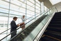 Business people talking on mobile phone and using digital tablet on escalator in a modern office Royalty Free Stock Photo