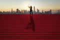 Side view of businessman silhouette with telescope looking into the distance on red stairs with shadow and city skyline in the