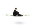 Side view businessman sitting on money flying carpet