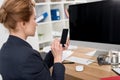 side view of businesswoman in suit using smartphone at workplace Royalty Free Stock Photo