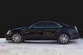 Side view of Cadillac CTS in black color after cleaning before sale in a winter day background on parking above black wall