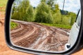 Side view with car rear view mirror on dirty clay road surrounded in natural landscape in a suumer day Royalty Free Stock Photo