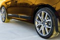 Side view of a car. Tire and alloy wheel of a modern gold car on the ground at the sunset. Car exterior details.