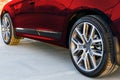 Side view of a car. Tire and alloy wheel of a modern red car on the ground at the sunset. Car exterior details. Royalty Free Stock Photo