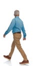 Side view of casual old man with sneakers looking away and walking Royalty Free Stock Photo