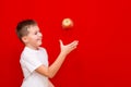 Side view Caucasian boy kid child schoolboy throw up apples Vitamins and fruits, healthy food. bright red wall