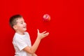 Side view Caucasian boy kid child schoolboy throw up apples Vitamins and fruits, healthy food. bright red wall