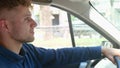 Side view of Caucasian handsome joyful male driver sitting in car with his hands on steering wheel driving a vehicle Royalty Free Stock Photo