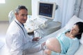 Male doctor doing ultrasound scan for pregnant woman in hospital Royalty Free Stock Photo