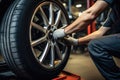 Side view of Caucasian male mechanic repairing car wheel in auto repair shop, Car mechanic working in garage and changing wheel Royalty Free Stock Photo