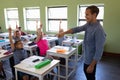 Male school teacher standing in an elementary school classroom with a group of school children Royalty Free Stock Photo