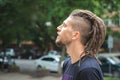 Side view of a caucasian man with dreadlocks and sidecut on a summer street