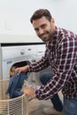 Man looking at camera while putting dirty clothes into the washing machine Royalty Free Stock Photo