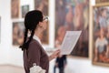 Side view of caucasian pretty young woman wearing glasses holds educational brochure. Defocused pictures in background Royalty Free Stock Photo