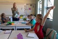 Schoolgirl sitting at a desk raising her hand in an elementary school classroom Royalty Free Stock Photo