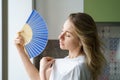 Overheated woman in t-shirt using wave fan suffer from heat sweating, cools herself, feels sluggish