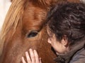 Side view of woman stroking a piebald pony