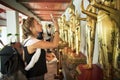 Side view of caucasian woman taking photo of Buddha statue in Thai temple