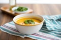 side view of a ceramic bowl filled with tomato basil soup on a linen napkin Royalty Free Stock Photo