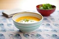 side view of a ceramic bowl filled with tomato basil soup on a linen napkin Royalty Free Stock Photo