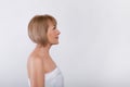 Side view of charming mature lady in bath towel on light studio background, copy space Royalty Free Stock Photo